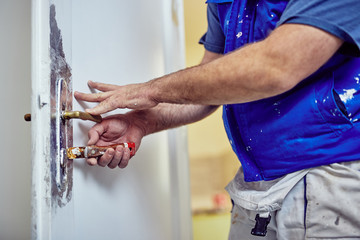 Handyman using chisel around doors lock tto scrub the old paint.