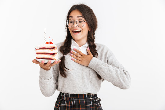 Photo closeup of happy teenage girl wearing eyeglasses smiling while holding big slice of birthday cake