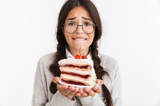 Photo closeup of stressed teenage girl wearing eyeglasses feeling sad while holding big slice of birthday cake