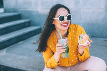 Plus size woman walking down the city and eating burger