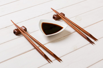 Soy sauce with chopsticks on white wooden table background