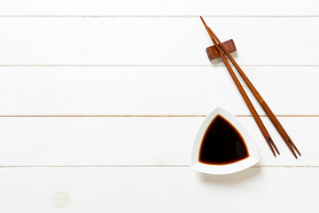 Soy sauce with chopsticks on white wooden table background