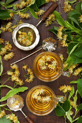 Glass of herbal tea with linden flowers on  old wooden background