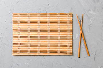 two sushi chopsticks with empty bamboo mat or wood plate on stone Background Top view with copy stace