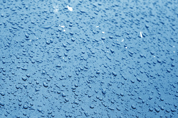 Water drops on car surface in navy blue tone.