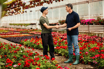Happy plant nursery workers greeting and shaking hands.