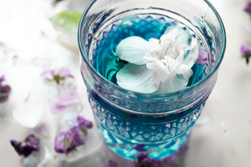 Glass with blue cocktail. Jasmine flower