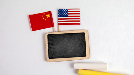 United States of America and Chinese flags. Small whiteboard with chalk. Top view on a white background. Mockup, copy space.