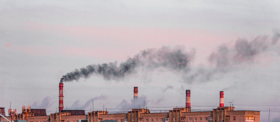 panoramic view of industrial chimneys with black smoke and toxic poisonous gases during the sunset