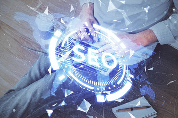 Multi exposure of seo icon with man working on computer on background. Concept of search engine optimization.