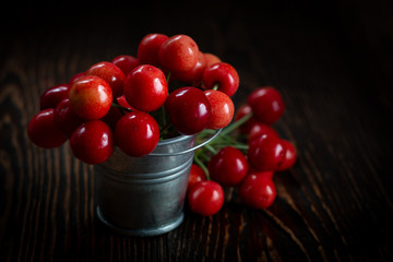 Fresh red Cherries in small metal bucket on old wooden background rural style