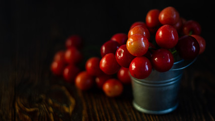 Fresh red Cherries in small metal bucket on old wooden background rural style