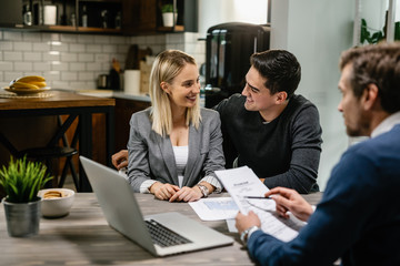 Happy couple communicating while having a meeting with financial advisor at home.