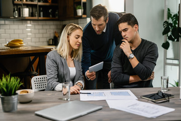 Young couple using digital tablet with their real estate agent.