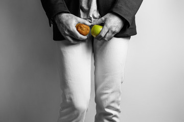 A man at the level of the genitals , holding a ripe and rotten apple. Disease for men. The concept...