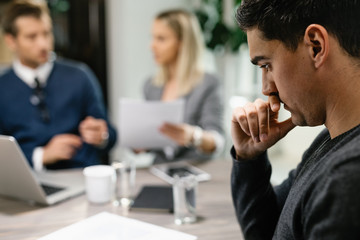 Young pensive man thinking of something on a meeting with financial advisor.