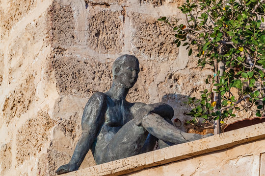 Sculpture black figure of sitting man in Jaffa Port.