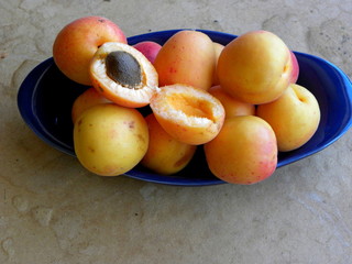 fresh apricots in bowl on wooden table. apricot pits