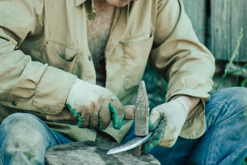 traditional iron forging, artisan sharpens a sharp knife blade with a hammer.