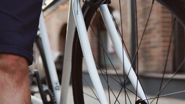 4k Close up of casual man bicyclist driving a white road bike in the city