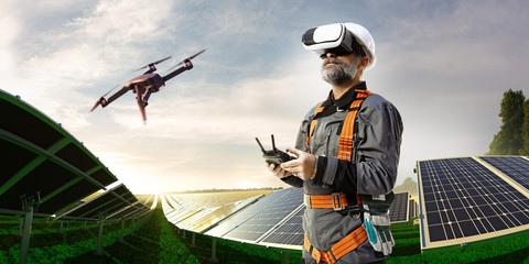 Happy engineer using drone and vr helmet for cheking solar station.