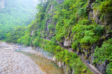 Fototapeta na wymiar Beautiful Taroko gorge in Taroko National Park, Taiwan photographed on a misty, rainy day. Rocks, green trees, high humidity. Tourists hiking