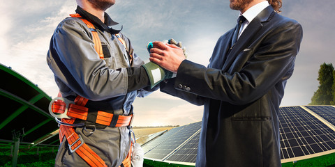 engineer and businessman shake hands. Around wind solar station and beautiful landscape