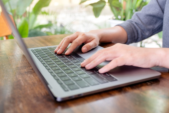 Closeup image of hands using and typing on laptop computer keyboard on the table