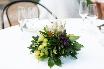 Table setting for a romantic dinner. Bouquet with bunches of grapes ,laurel leaves