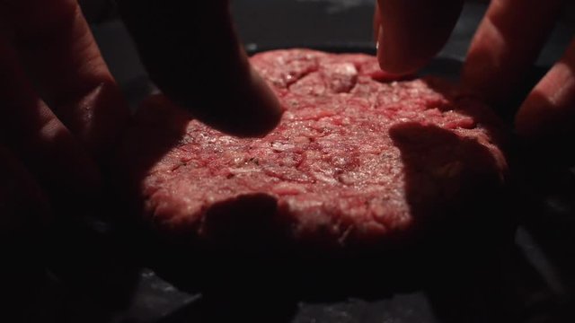 Close-up of chef cook taking a cutlet from the black pan for cooking hamburgers. Stock footage. Chef making hamburger patty in kitchen with ground beef