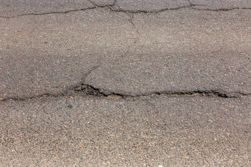 Damaged road, asphalt cracks. Asphalt with potholes and asphalt overflow spots. Very bad asphalt road with big holes. Scary technology in road construction. Numerous dangerous failures.