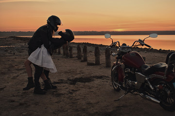 Romantic biker couple in leather and helms with red motorcycle. Woman and man against motorcycle...