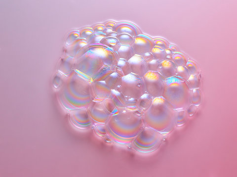 Cluster of iridescent bubbles on pink surface