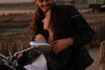 Close-up portrait of beautiful romantic biker couple in leather at sunset