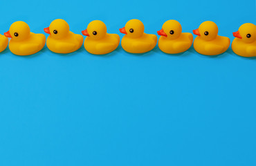 yellow rubber ducks in a close row on blue background with copy space