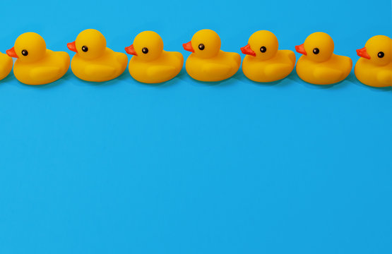 Yellow Rubber Ducks In A Close Row On Blue Background With Copy Space