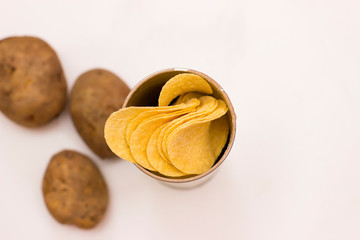 Potato chips with fresh potatoes on a white background