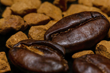 Coffee beans and instant coffee granules on a dark background