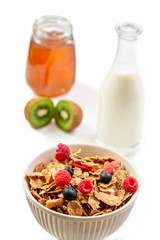 Healthy breakfast with bowl of cereal, orange juice, milk, , and fruits on white background.