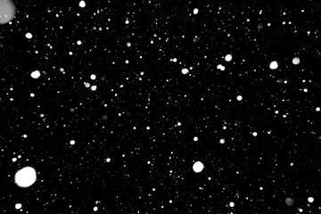 falling snow on a black background, snowfall at night, white chaotic spots on a black background