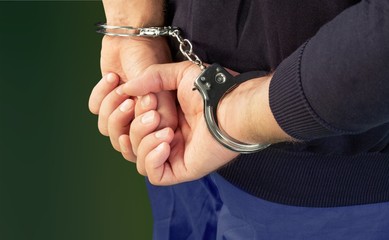 Cropped image of male hands in handcuffs behind his back