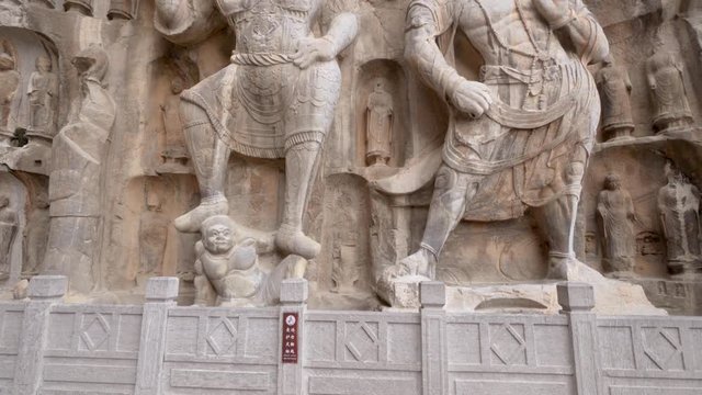 Giant temple guard statues at Fengxian Temple of Longmen Grotto. A massive buddhist sculptures in the main grotto at Longmen Caves, Luoyang, Henan province, China.