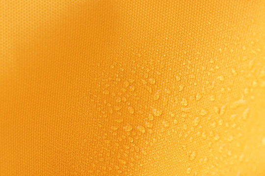 Waterproof and water repellent fabric.  Water drops on textile. Canvas of yellow fabric