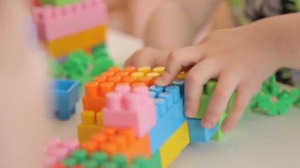 The boy plays a game designer. The child folds a multicolored plastic constructor. Color parts designer. Educational games for children.