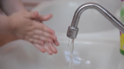 child washes his hands with liquid soap under the tap with water. A little girl or boy washes his hands under the stream of water. Hand washing against bacteria, hygiene and health