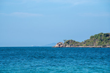 Naklejka premium Landscape wide shot elective focus of the sun glimmering sunlight peaking the waving sea surface in hot summer sunny day with blue sky, white clouds and mountains backgrounds