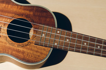 Ukulele closeup. Beige background.