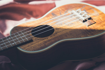 Obraz premium Ukulele closeup. Pink and bright background.