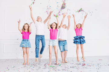 Obraz premium Happy beautiful cute kids smile at the holiday party with confetti together in the white room