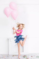 Obraz na płótnie Canvas Happy beautiful cute child girl with smile at holiday party with balloons and confetti in white room